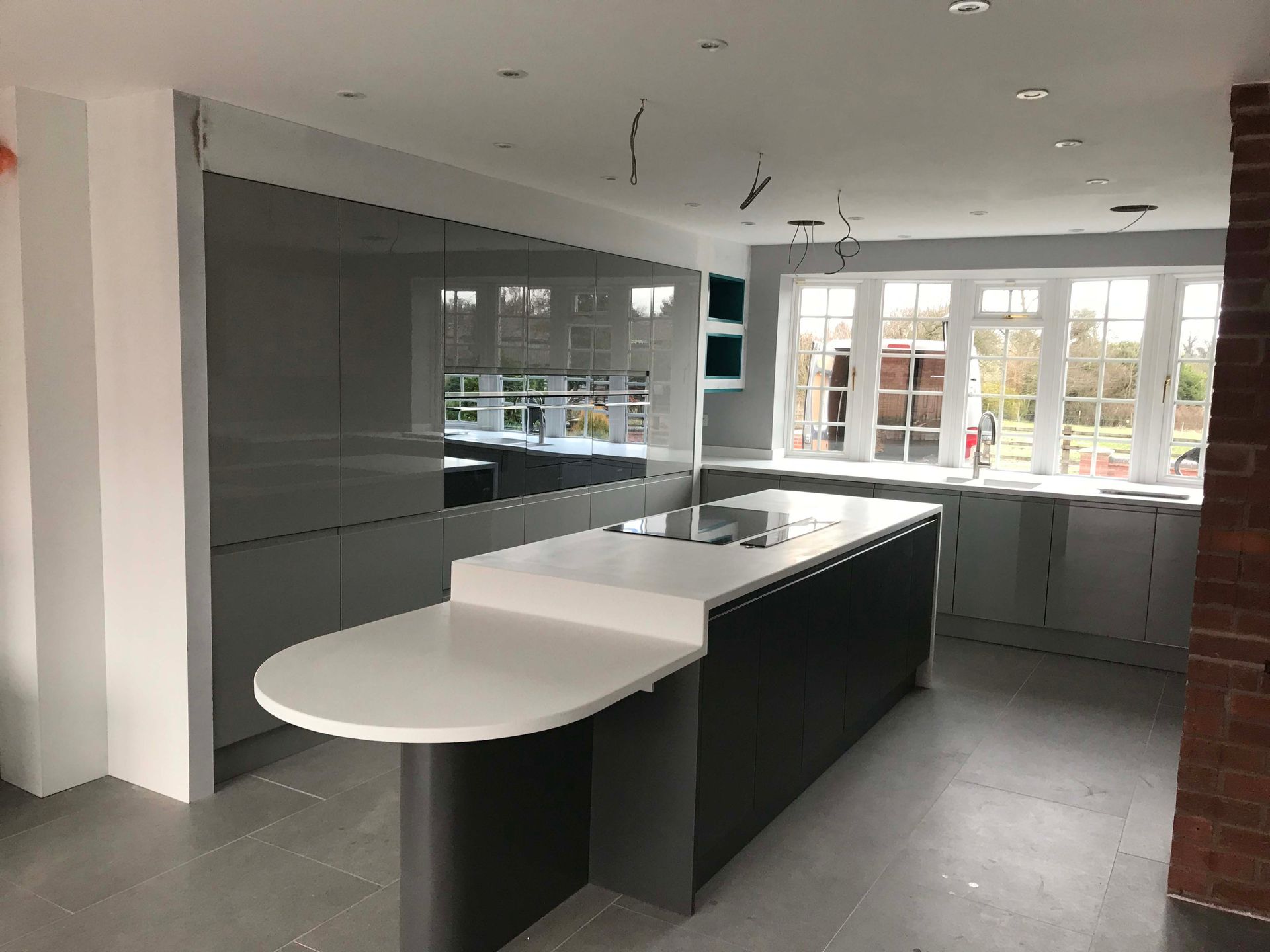 Modern kitchen with dark cabinets, white island countertop, and large windows.