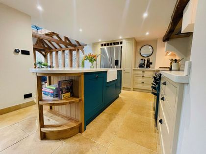 Bright modern kitchen with a teal island, wood floors, white cabinets, and pendant lights