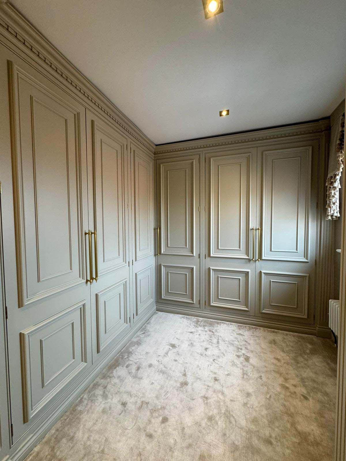 Empty carpeted room with gray built-in paneled wardrobes and recessed ceiling lights
