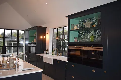 Modern kitchen with dark cabinets, white countertops, and large windows