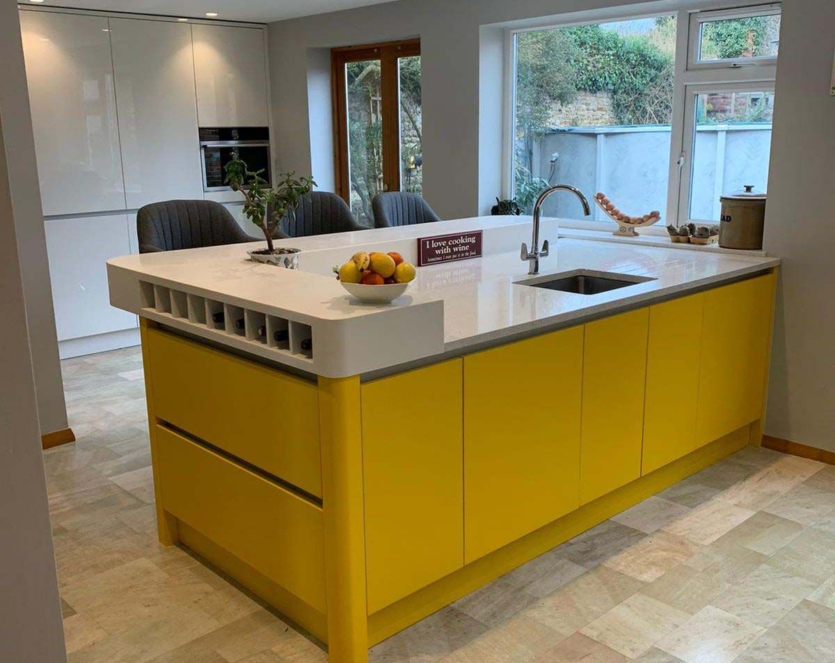 Bright kitchen with a yellow island, white countertop, and large window overlooking the yard