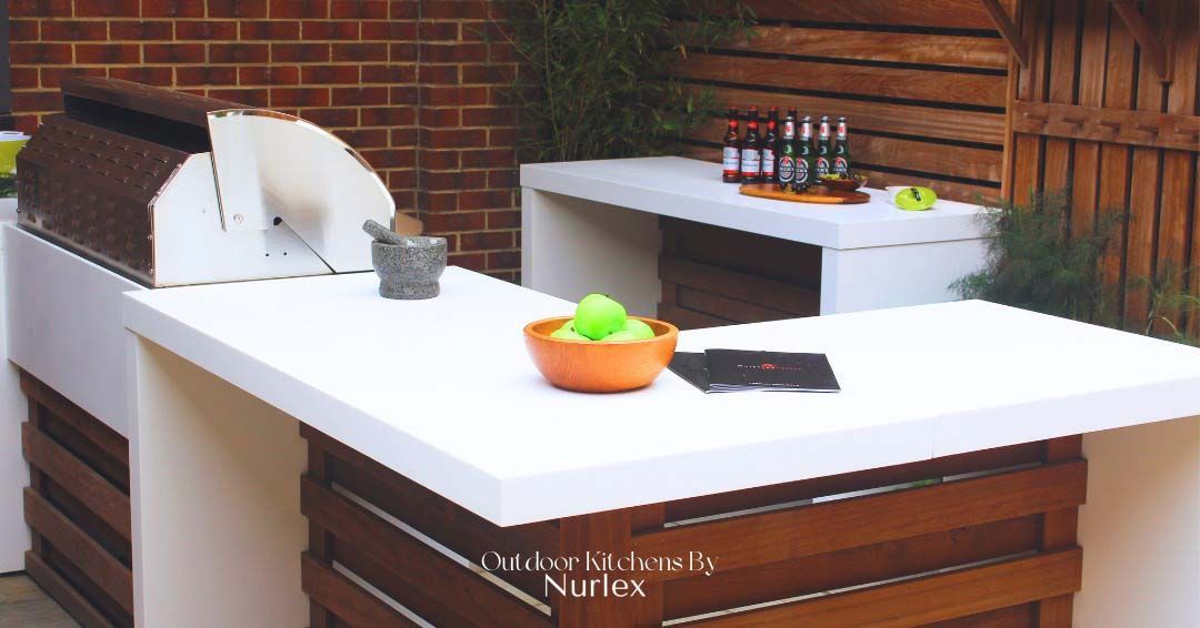 Empty modern kitchen with white countertops, brown cabinets, and a bowl of oranges on the island.