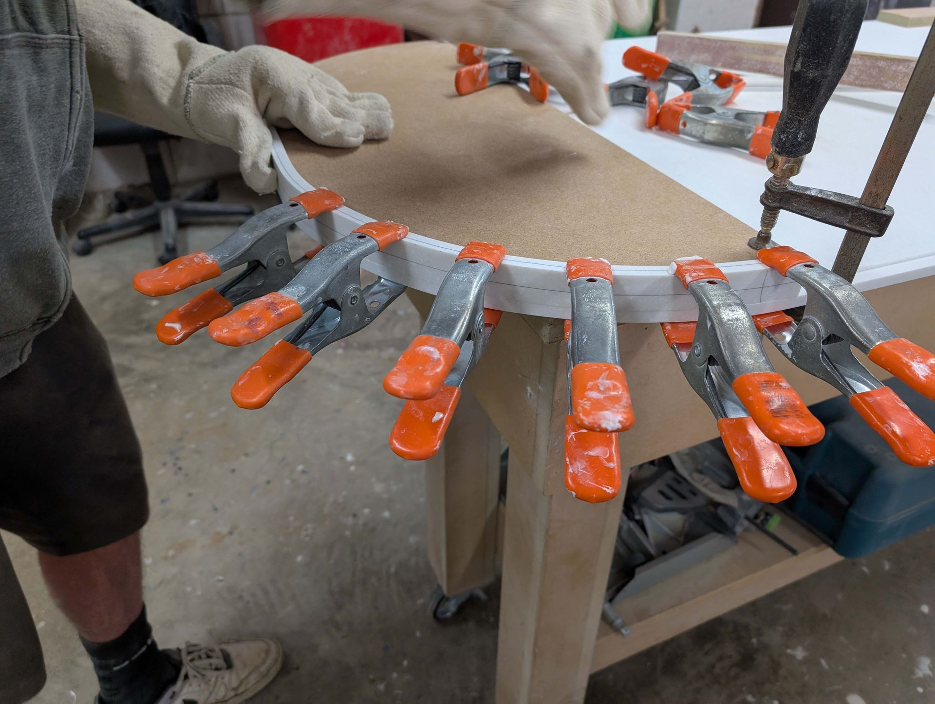 Hands clamped around a curved board on a workbench in a workshop