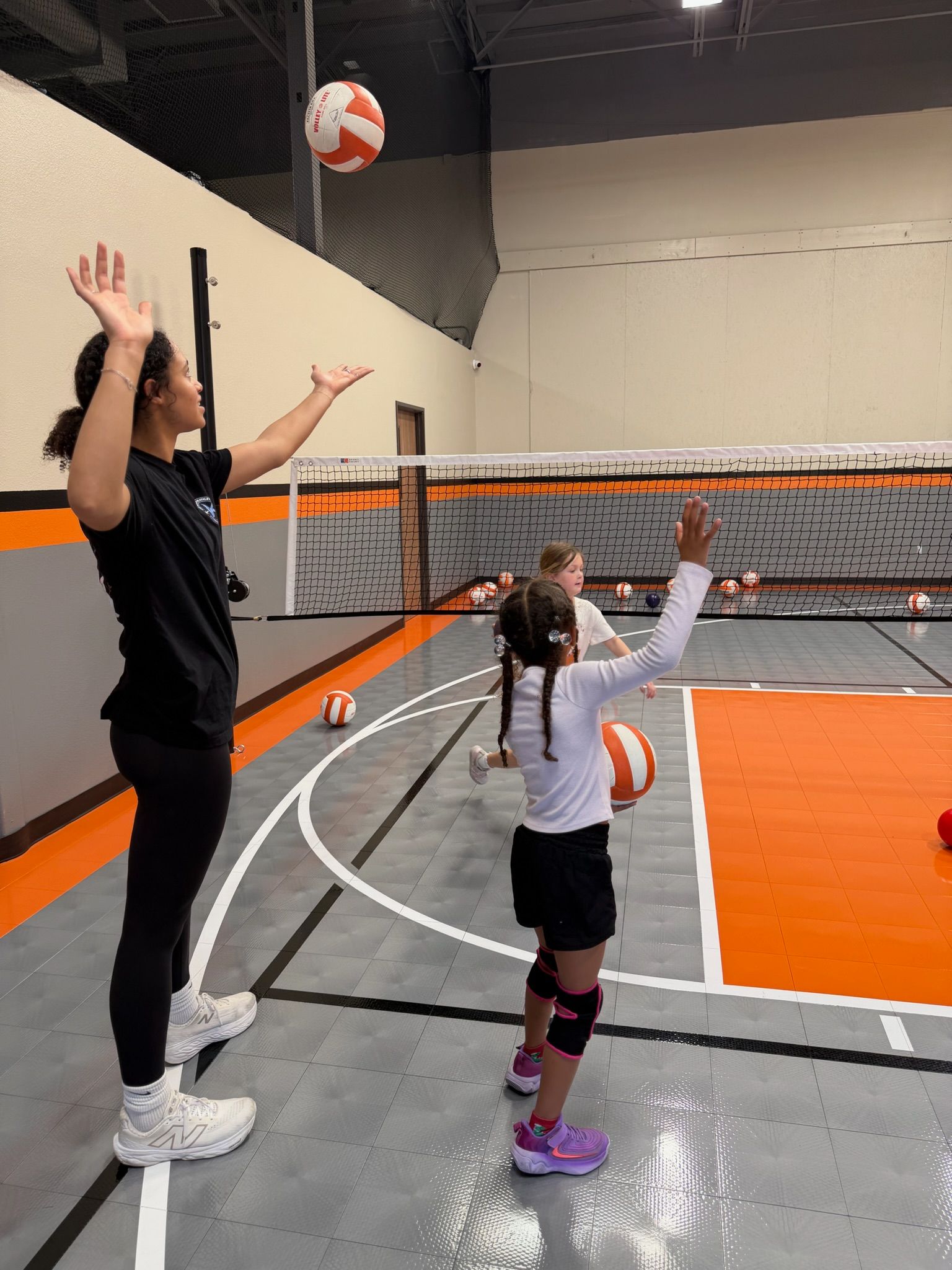 A group of children are doing stretching exercises in a gym.