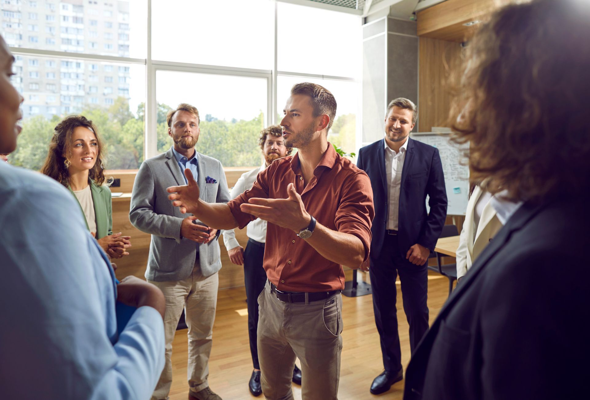 Small group in a bright office discussing ideas, with one man gesturing while others listen attentively.