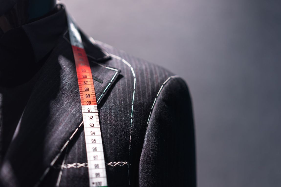 Tailor’s dress form in black fabric with a measuring tape draped over the shoulder