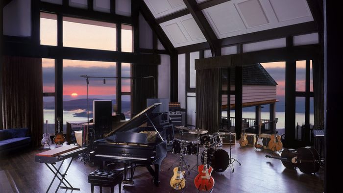 A room with a piano drums and guitars in it