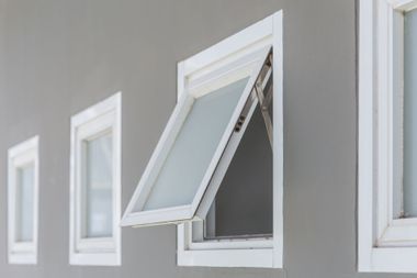 White-framed window, one open to let in air, against gray wall.