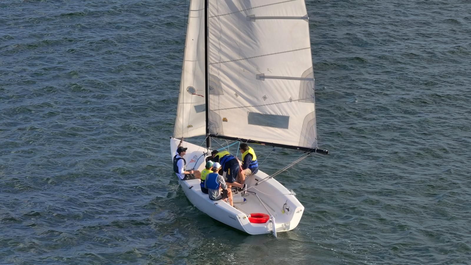 Sailboat with several people aboard on open water, viewed from above. — Gosford Sailing Club in Gosford, NSW