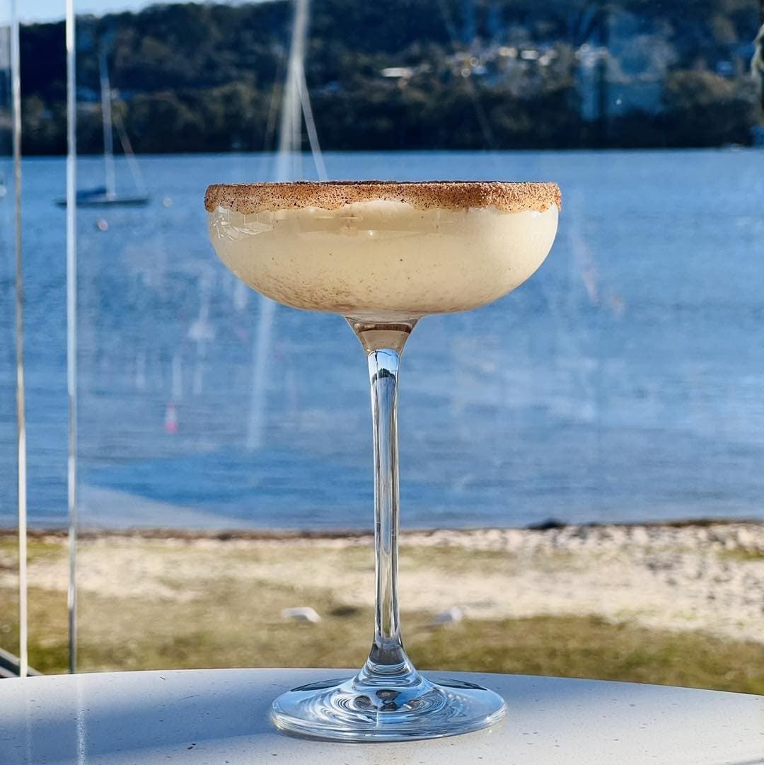 A Martini Glass Sitting on a Table in Front of a Body of Water — Gosford Sailing Club in Gosford, NSW