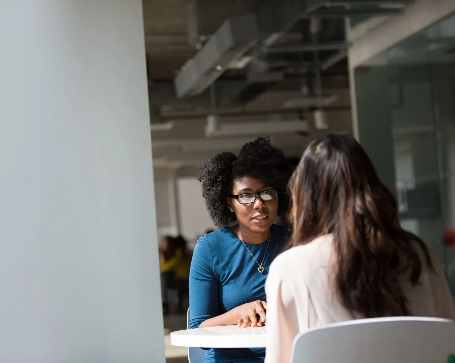 Two women are sitting at a table having a conversation.