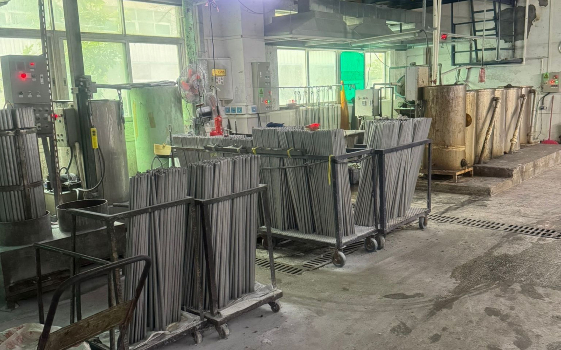 Industrial workshop with metal racks, machinery, and stacked materials on a concrete floor