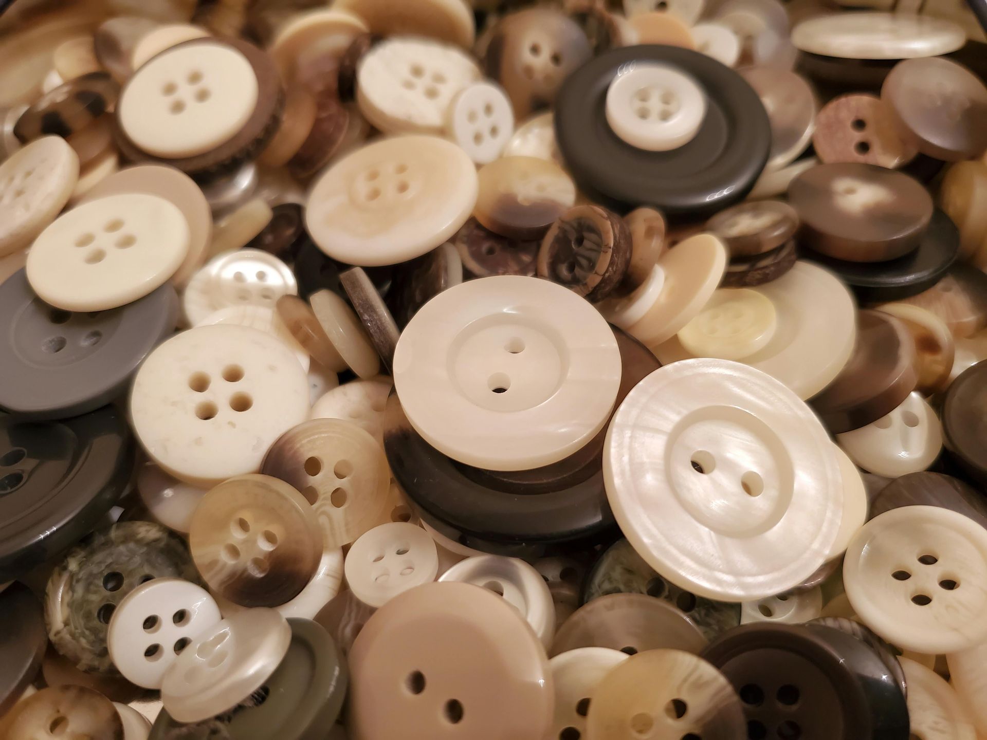 Assorted beige, brown, and white buttons piled together in a close-up view