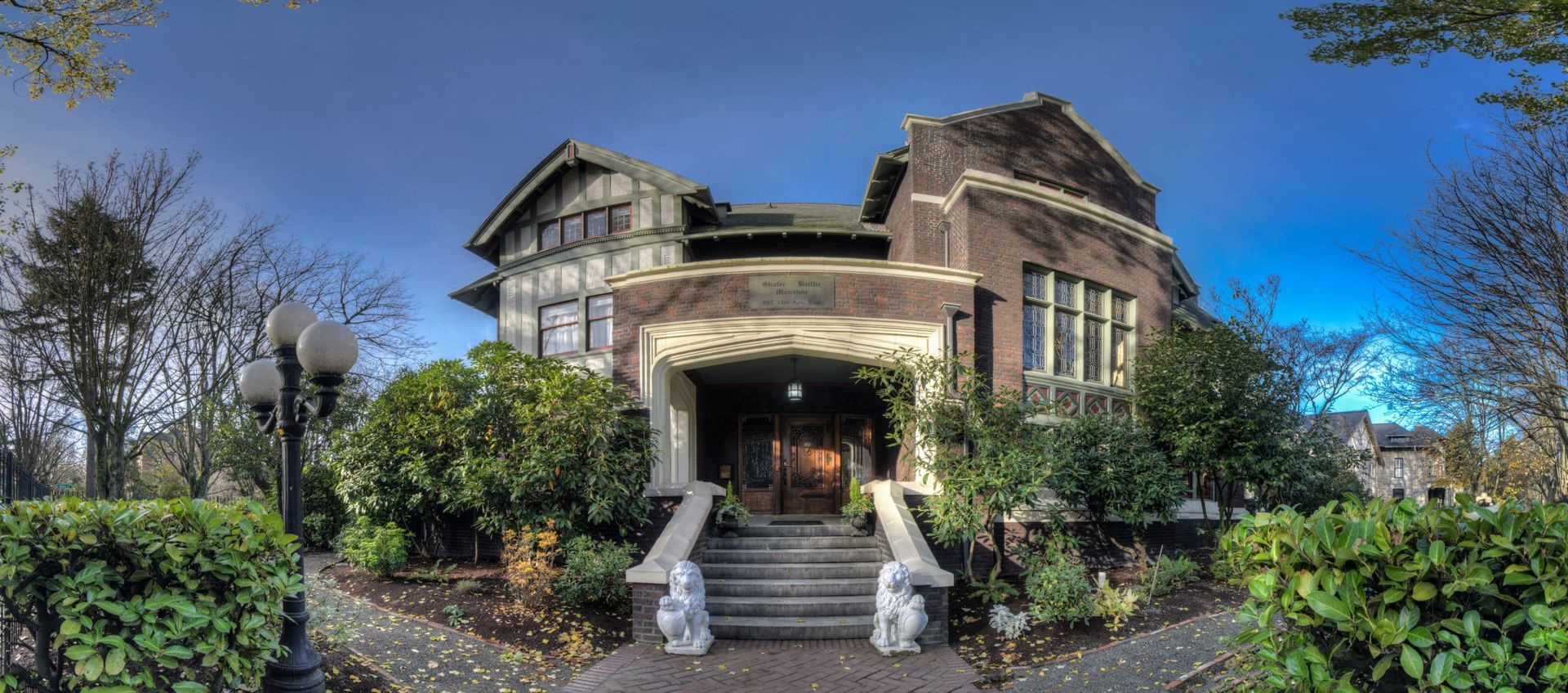 A large brick house is surrounded by trees and bushes.