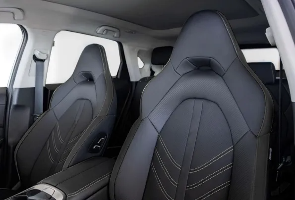 Interno di un'auto con due sedili anteriori in pelle nera e abitacolo grigio chiaro.