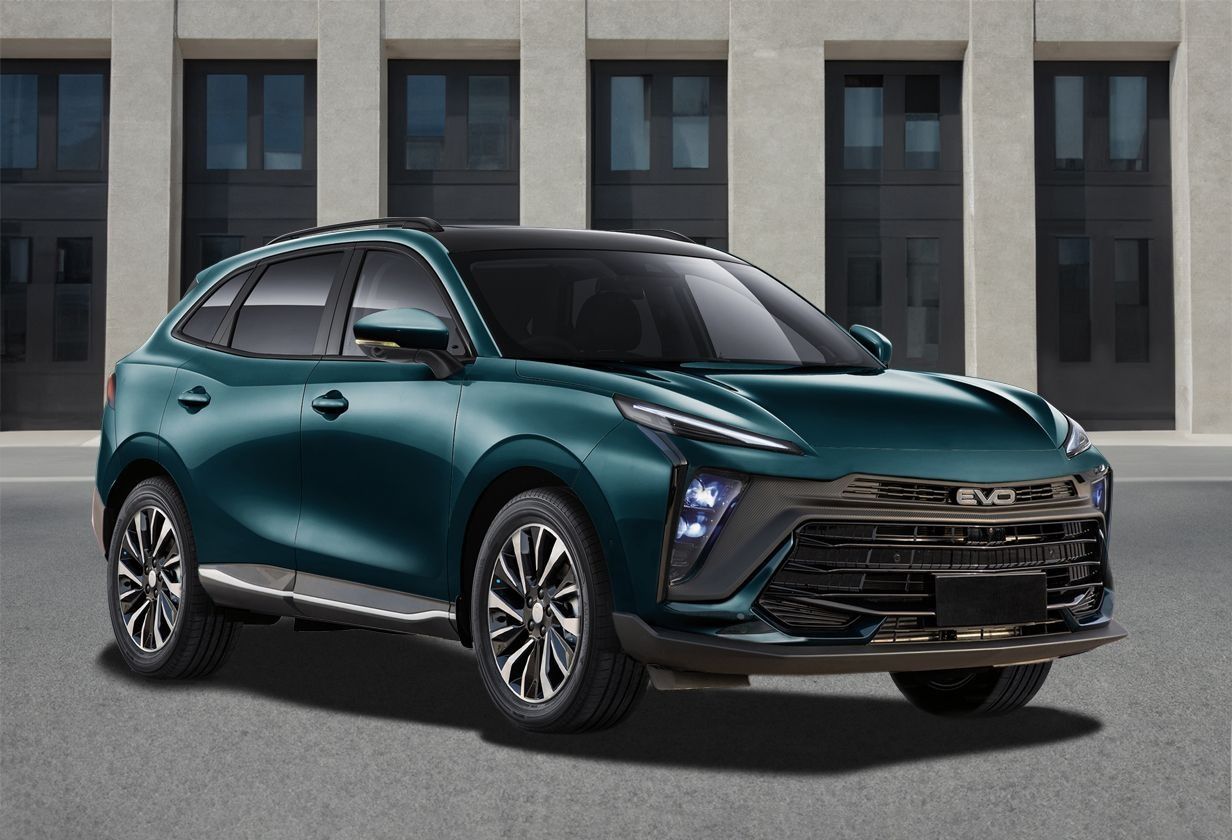 Un SUV color verde acqua parcheggiato davanti a un edificio moderno.