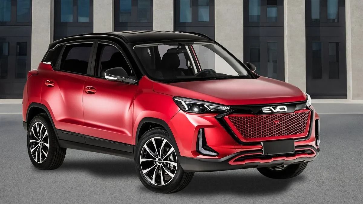 SUV compatto rosso con tetto e finiture nere, parcheggiato sul marciapiede di fronte a un edificio moderno.