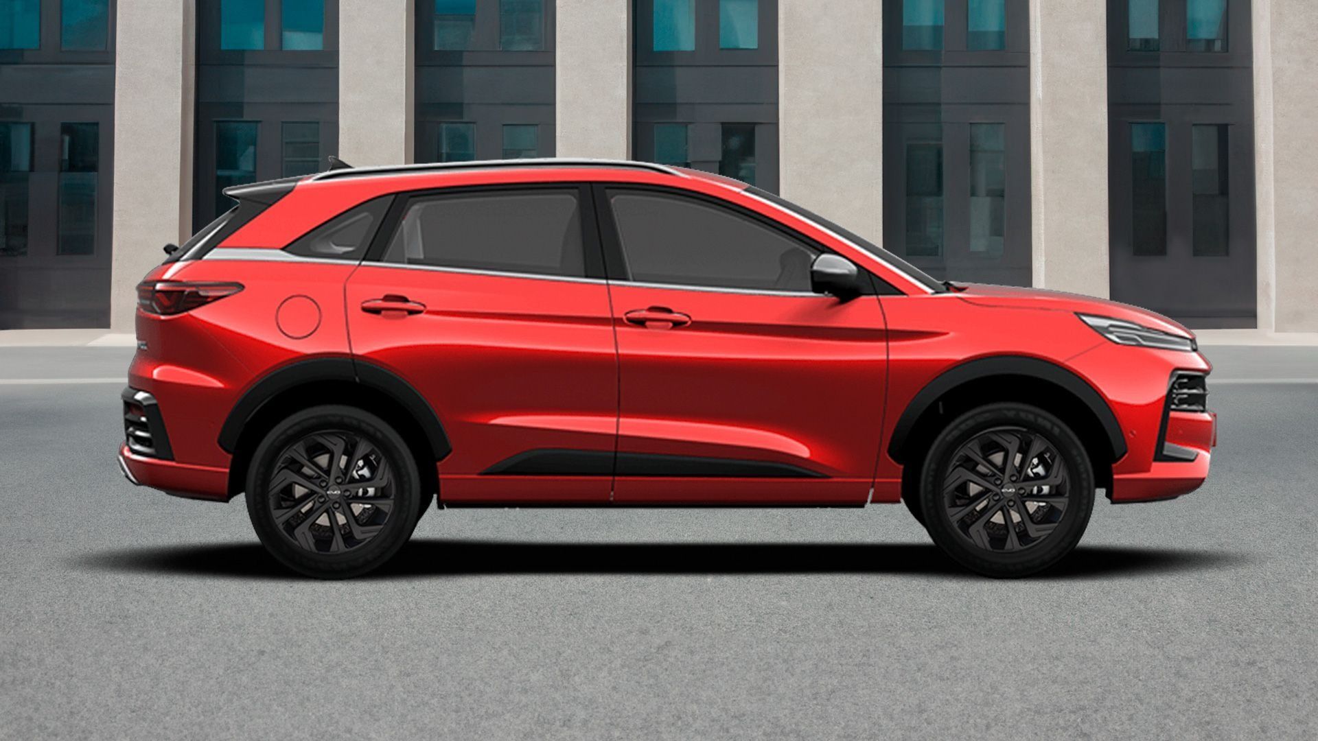 Un SUV rosso parcheggiato di profilo su una strada con edifici sullo sfondo.