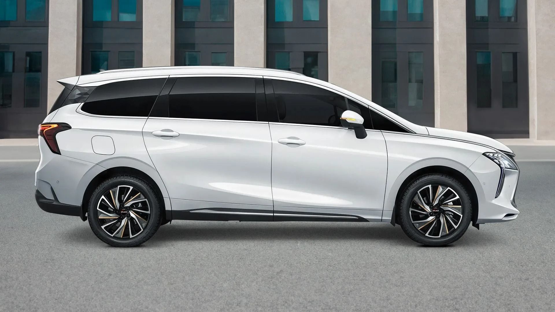 Minivan bianco parcheggiato davanti a un edificio, vista laterale.
