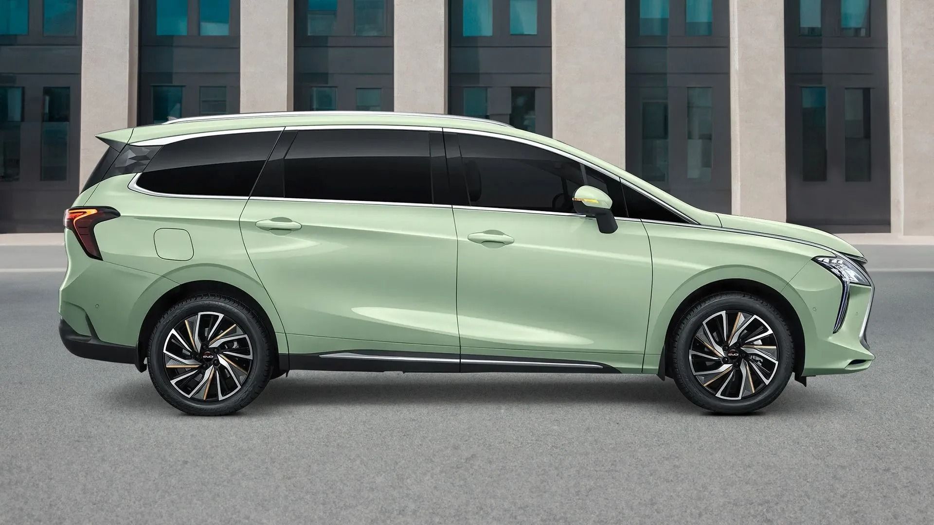 Minivan verde chiaro parcheggiato di traverso davanti a un edificio