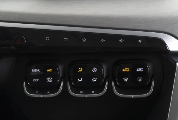 Pannello di controllo del climatizzatore nella console centrale dell'auto con pulsanti e bocchette illuminati.