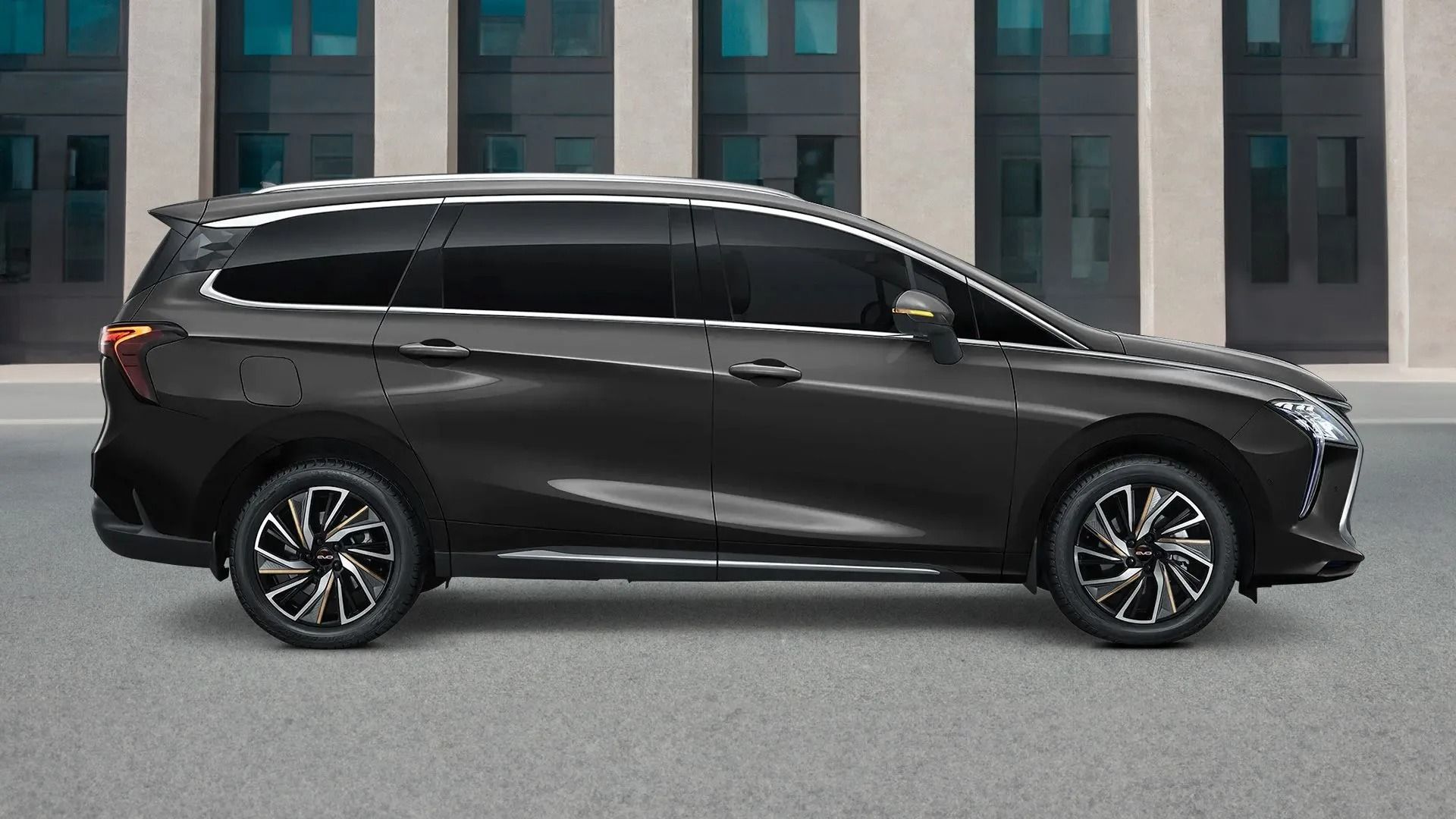 Un SUV grigio scuro, visto di profilo, è parcheggiato davanti a un edificio moderno.