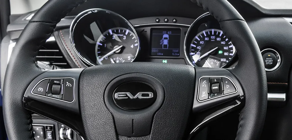 Vista interna di un'auto Nissan EVO: volante e cruscotto con indicatori illuminati.
