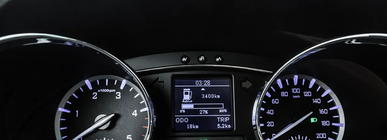 Cruscotto di un'auto di notte con tachimetro, contagiri e display centrale illuminati che mostrano le informazioni.