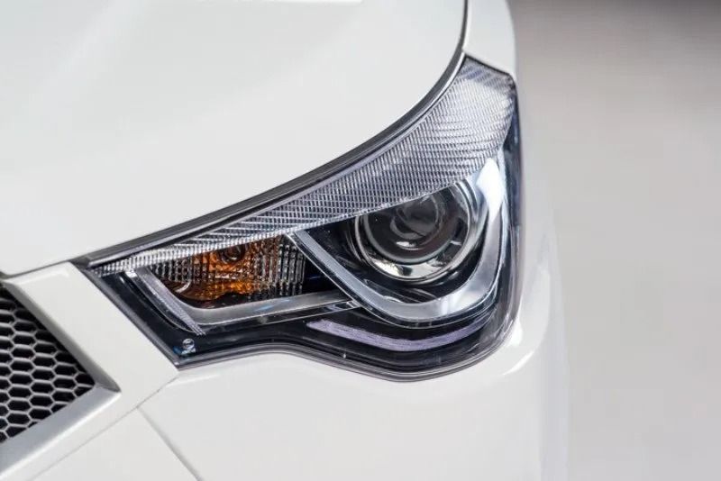 Primo piano del faro anteriore e della griglia di un'auto bianca.