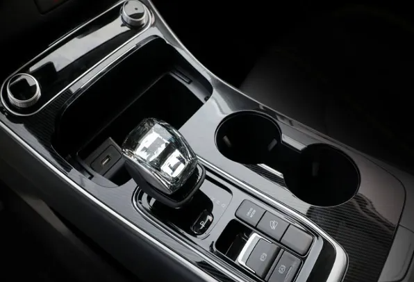 Console centrale dell'auto con selettore del cambio, portabicchieri e comandi del climatizzatore in interni neri