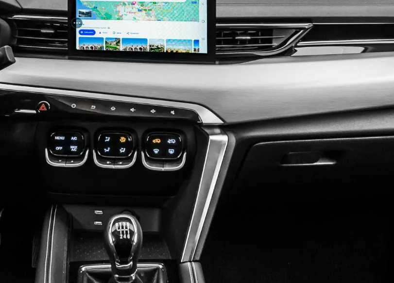 Cruscotto con console centrale dotata di touchscreen, comandi del climatizzatore e leva del cambio in un'auto moderna