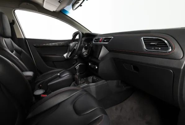 Interni neri dell'auto con sedili anteriori, cruscotto, volante e console centrale.