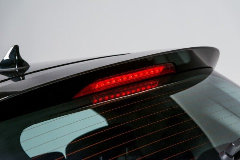 Lunotto posteriore rosso con luce di stop illuminata in posizione elevata e spoiler nero