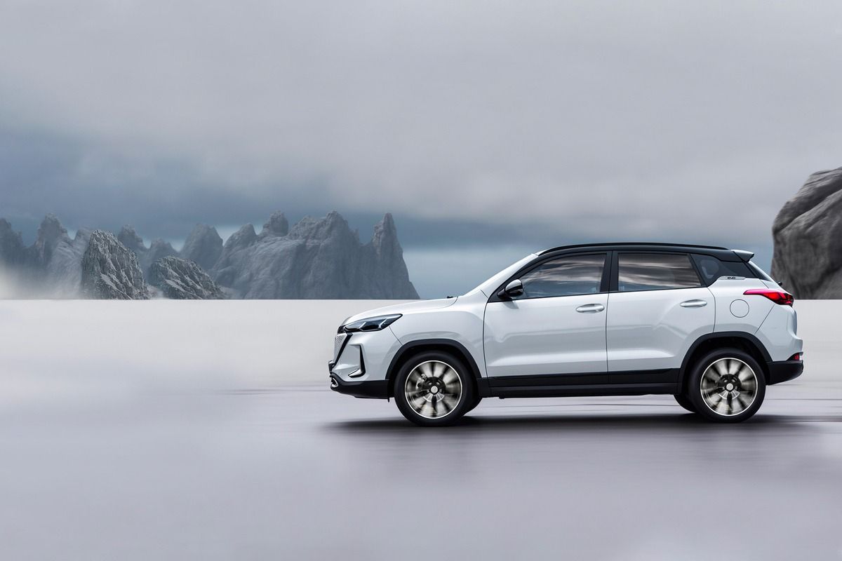 Un SUV argentato percorre una strada innevata con le montagne sullo sfondo.