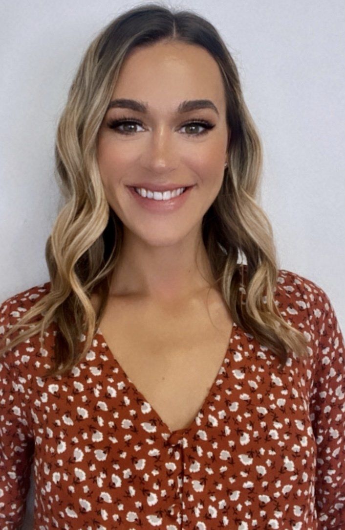 A woman in a red polka dot shirt is smiling for the camera.