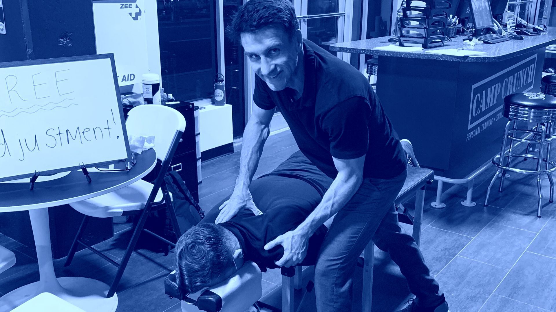 A man is sitting on a chair giving a massage to another man.