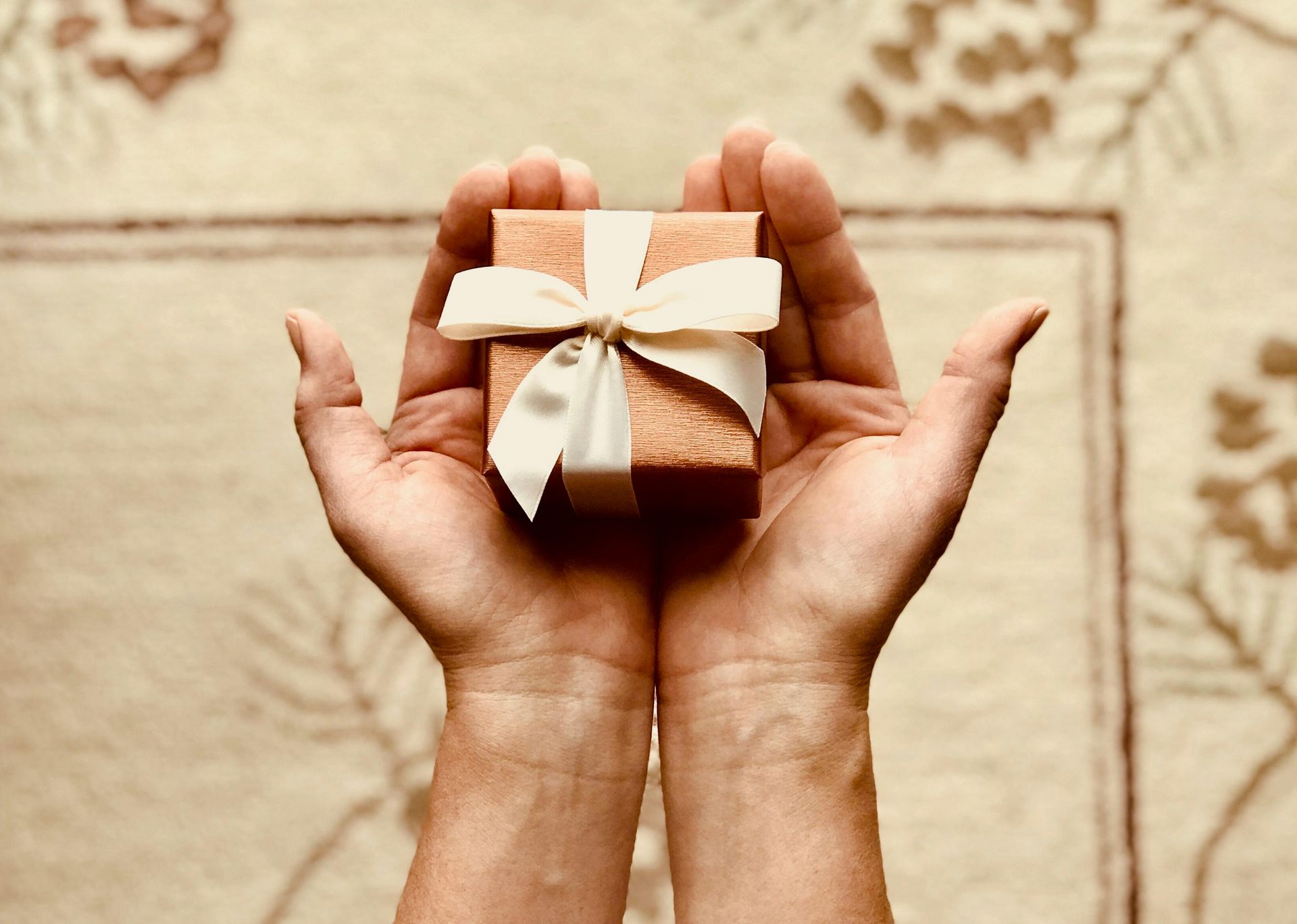 A pair of cupped hands holding out a gift box