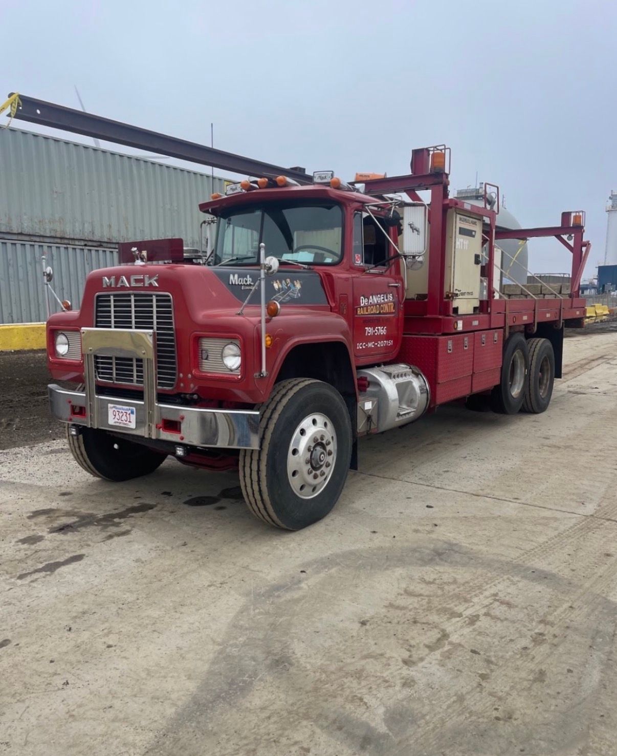 Red tow truck parked on a gravel lot beside an industrial building.