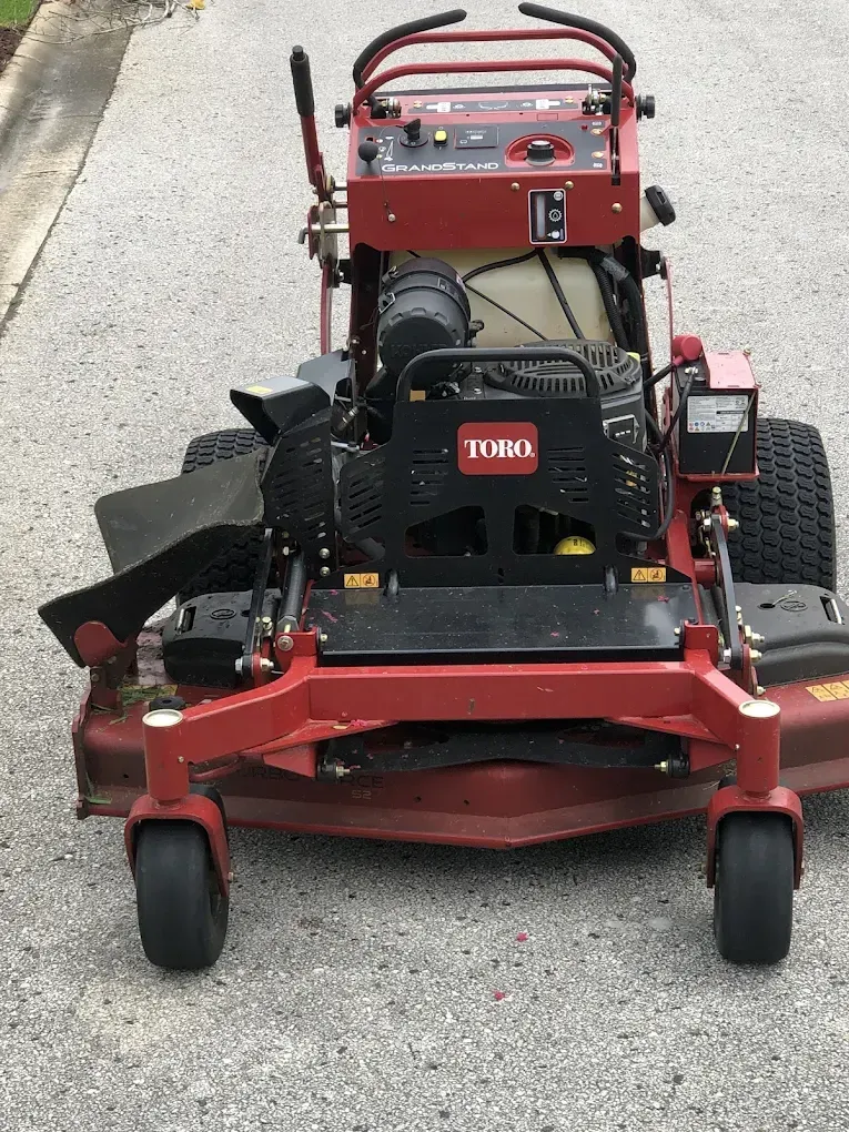 A red toro lawn mower is parked on the side of the road.