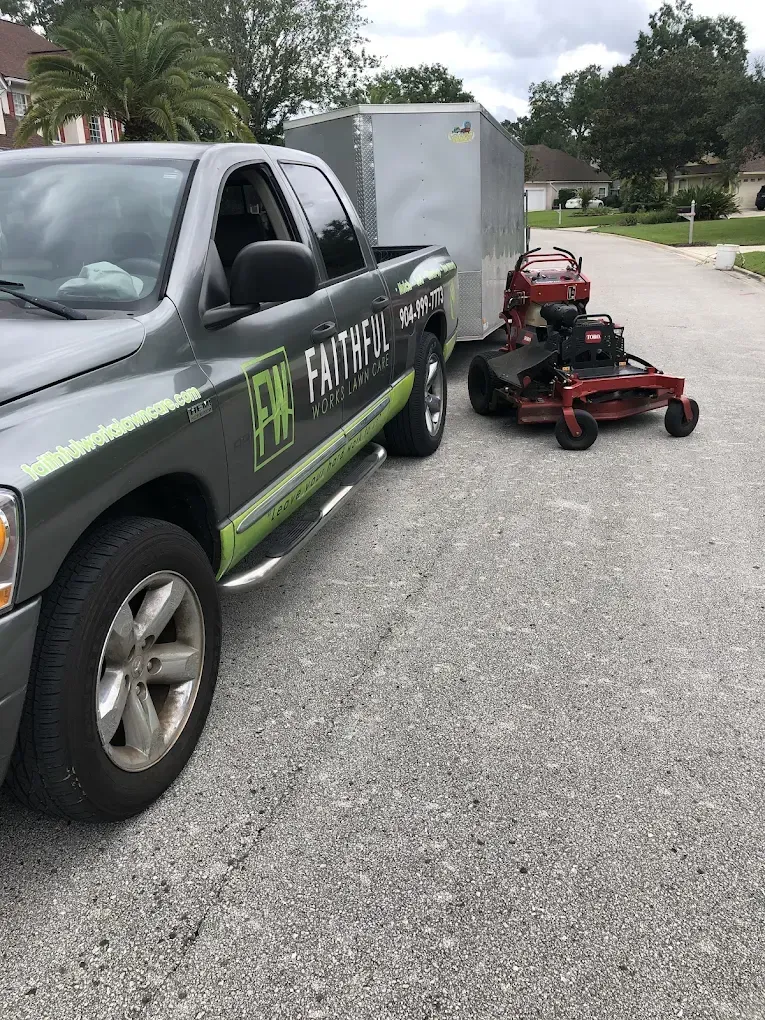 A truck is towing a lawn mower on a trailer.