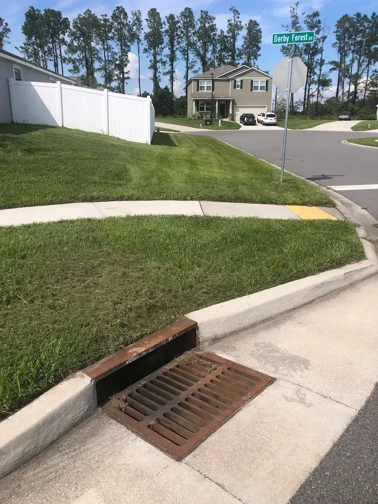 A manhole cover is sitting on the sidewalk in front of a house.
