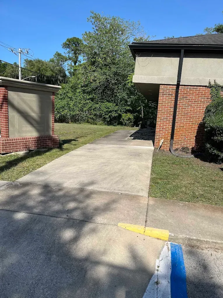 A brick building with a concrete walkway leading to it.