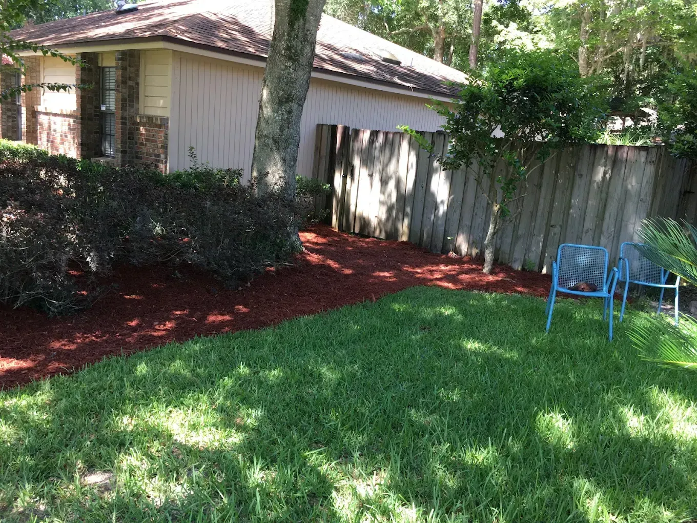There is a blue chair in the backyard of a house.