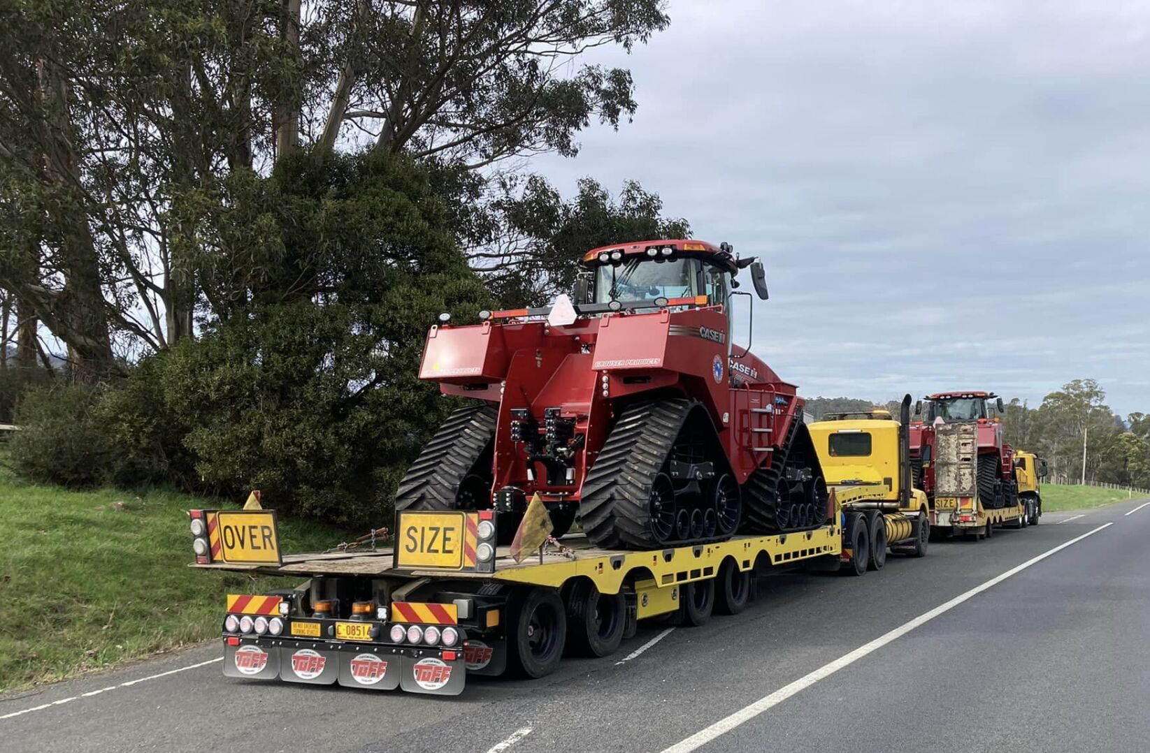 Emergency heavy vehicle towing of two large tractors on the road.