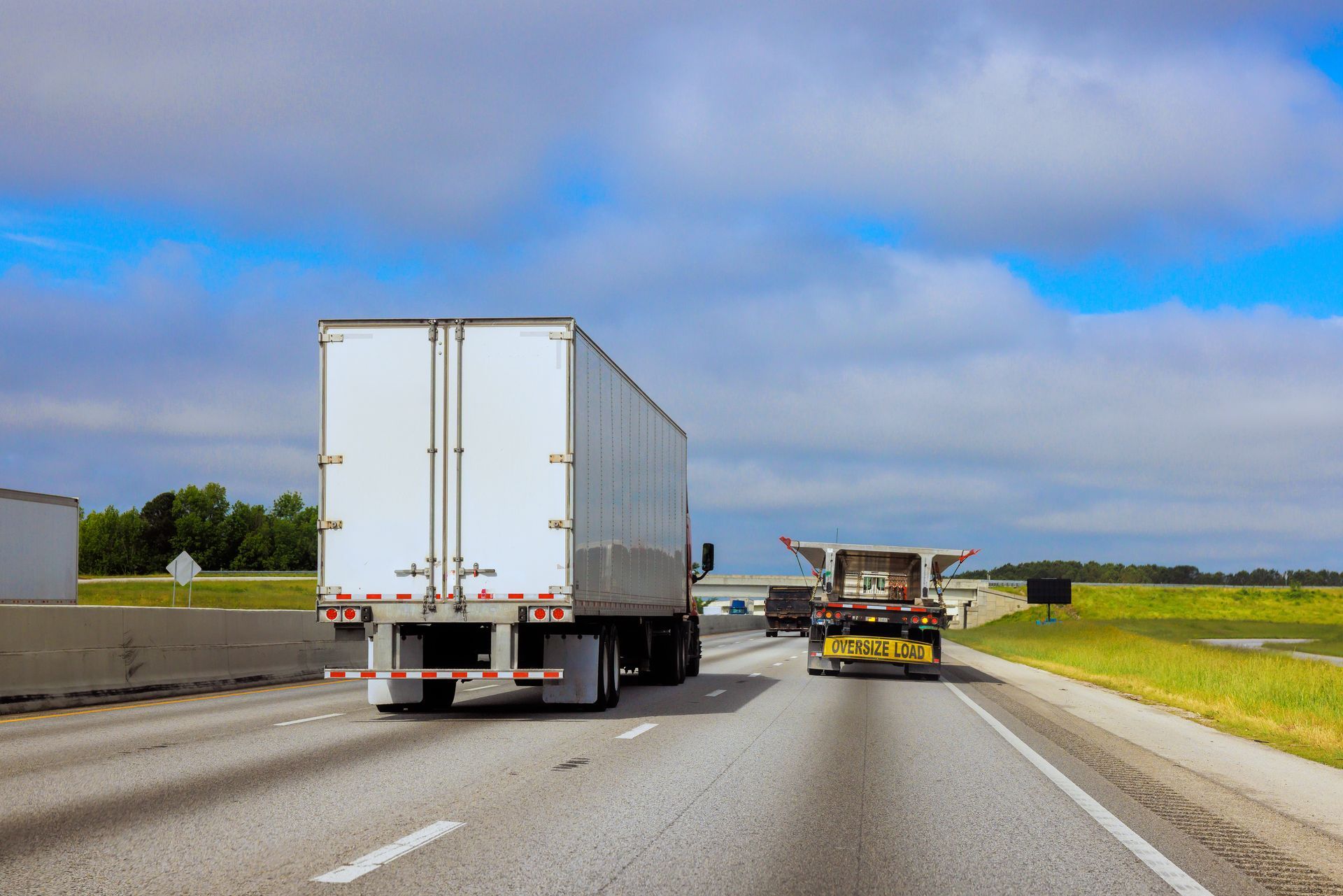 Large trucks travel on a highway, and a nearby vehicle is signalling for caution.