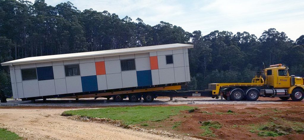 Emergency heavy vehicle hauling a modular building.