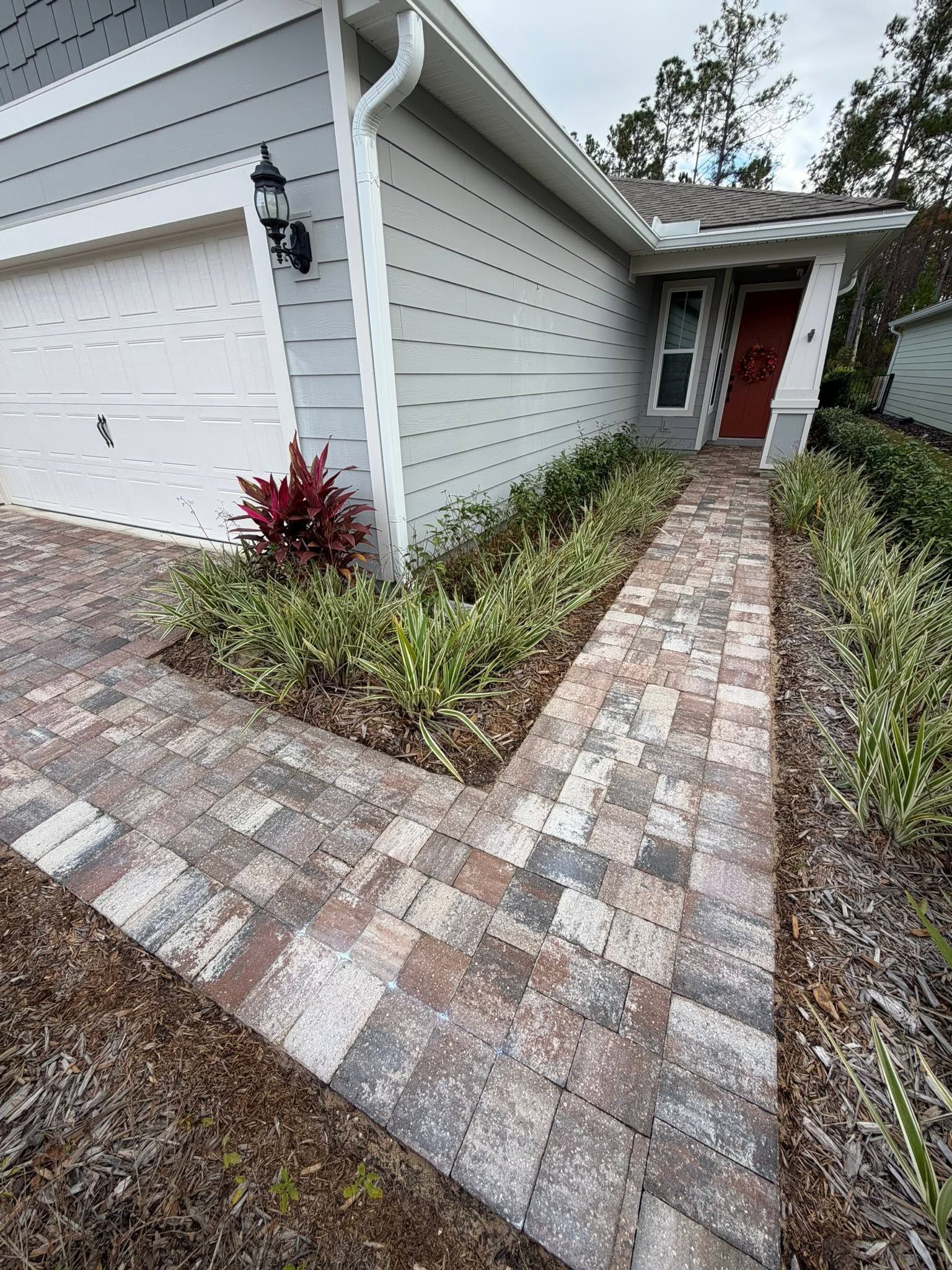 An unidentified person wearing boots is performing residential pressure washing on a driveway. An unidentified person wearing boots is performing residential pressure washing on a driveway.