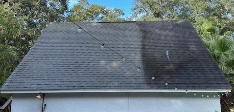 A roof being power washed, showing the difference between the cleaned and dirty sections.