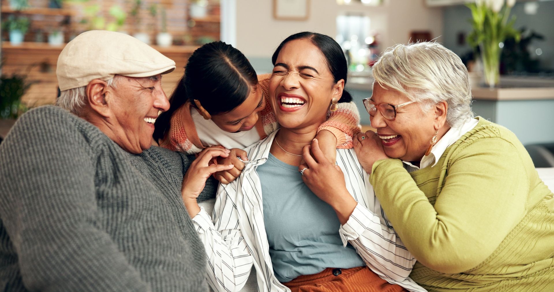 Four people laughing together on a couch in a cozy living room