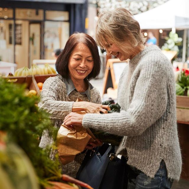 Two women are shopping for vegetables at a farmer 's market.
